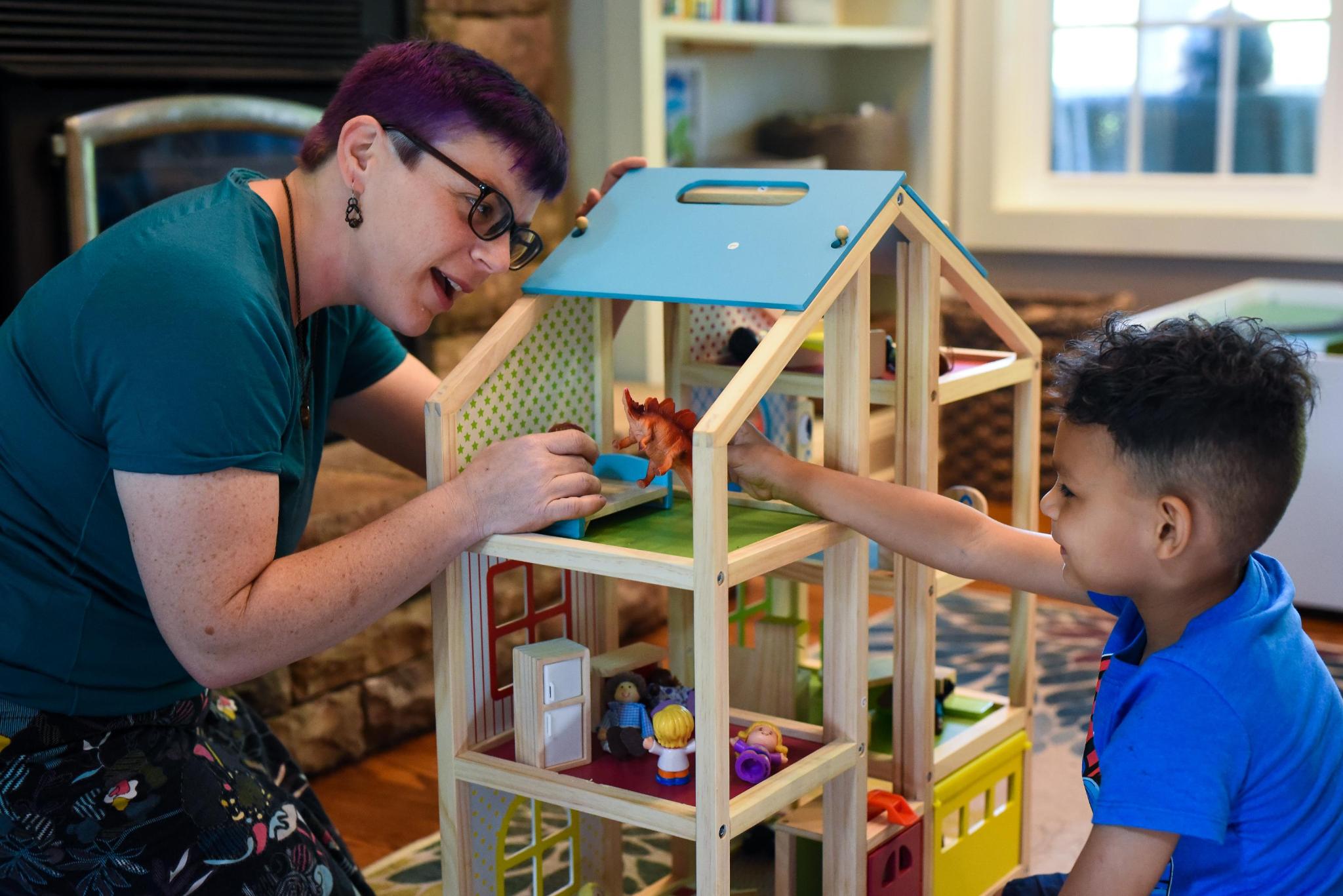 Adult and child playing doll house together